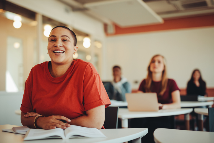 Female student sitting in university classroom and smiling.